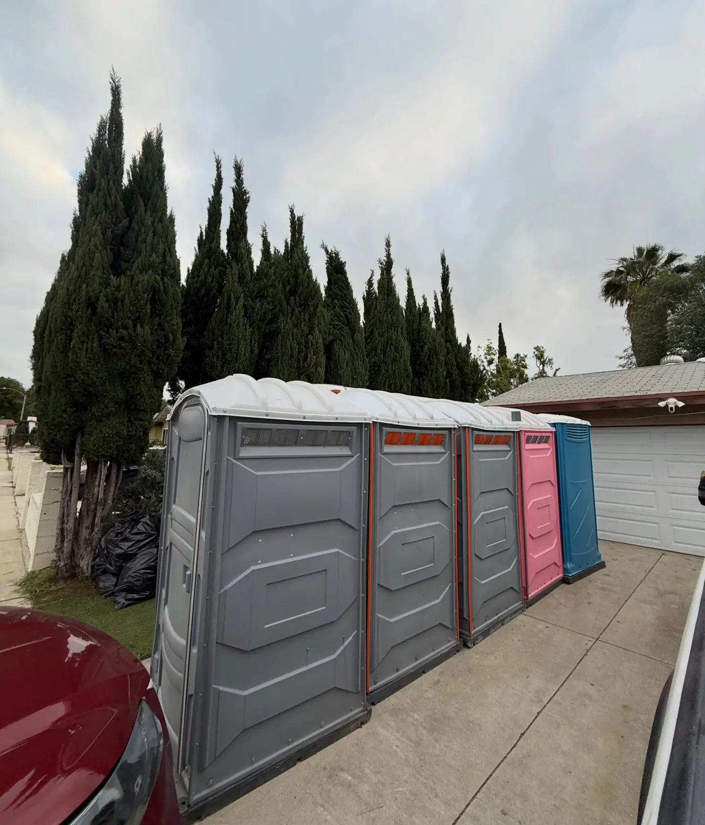 Row of gray and pink portable toilets along a jobsite fence
