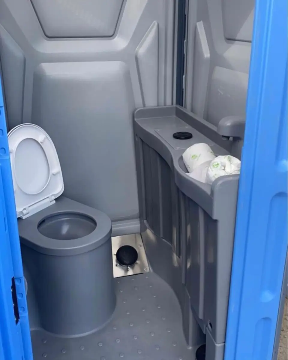 Inside a deluxe portable toilet with a molded sink and flushing toilet