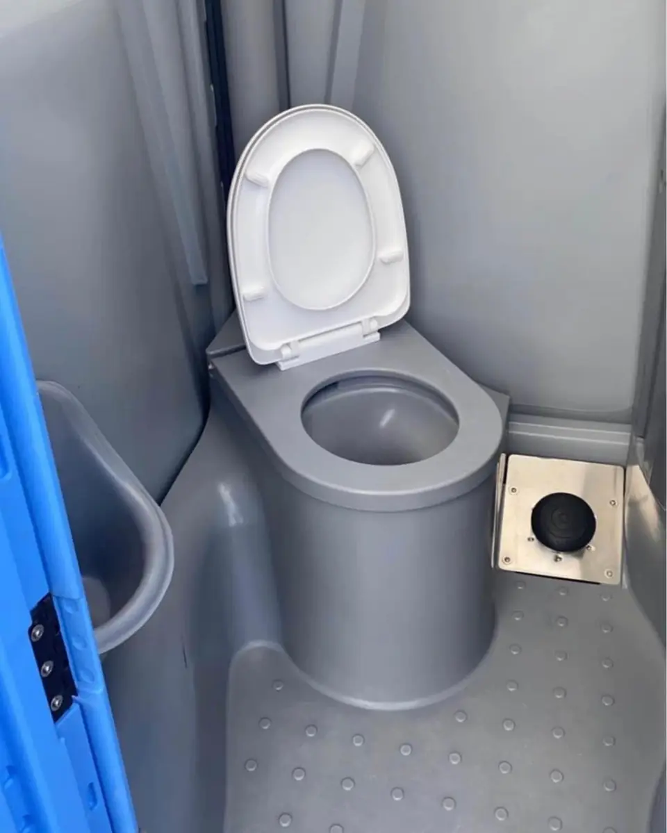 Gray interior of a roomy portable restroom with a toilet seat and grab space