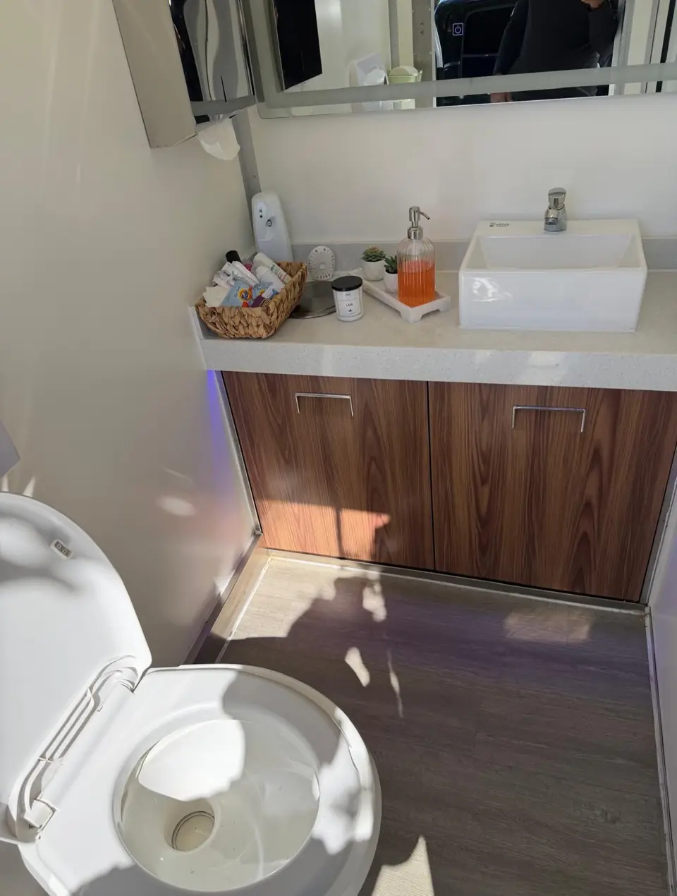 Wood-front vanity with vessel sink inside a luxury restroom trailer