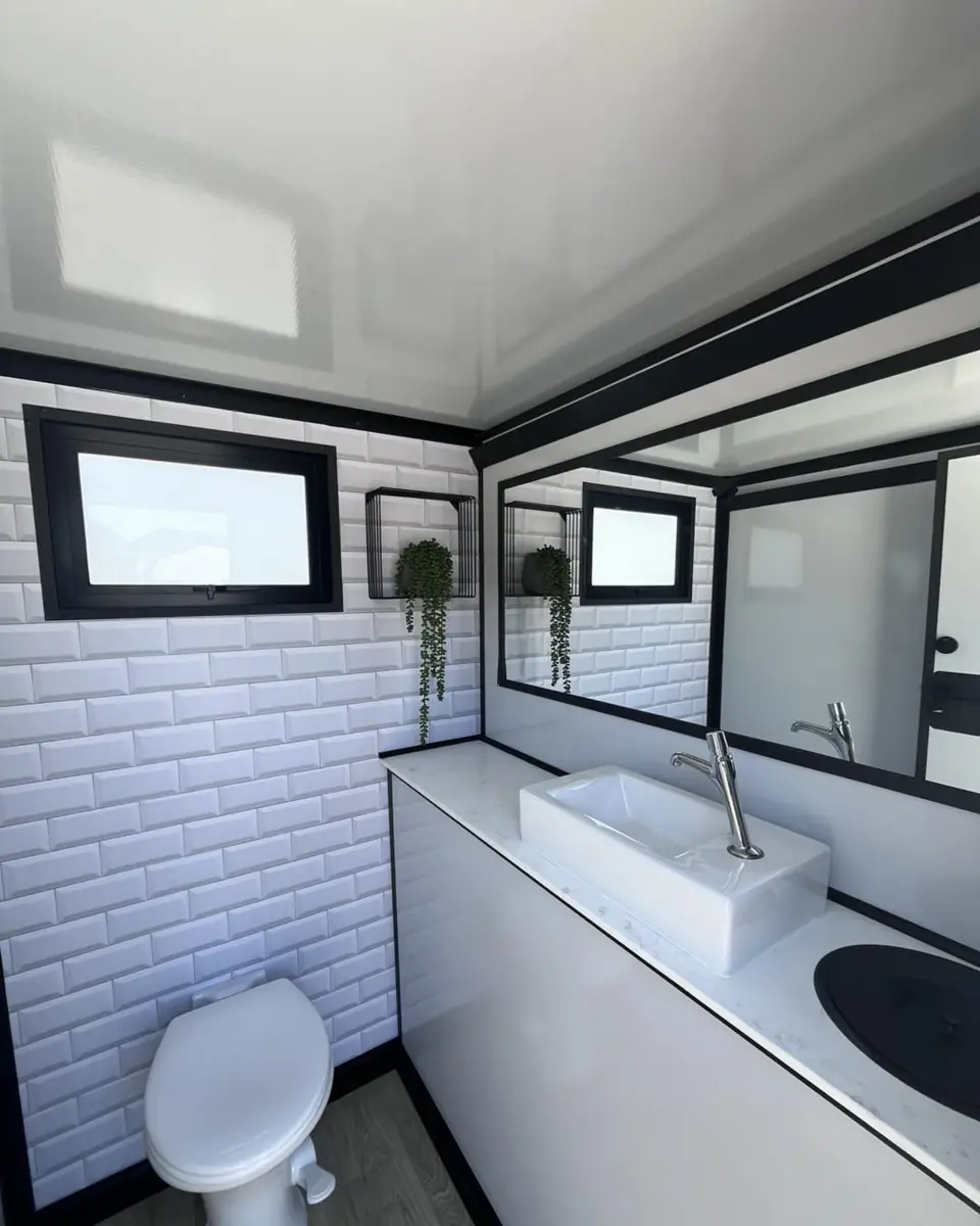 Restroom trailer interior with white tile wall, toilet and long sink counter