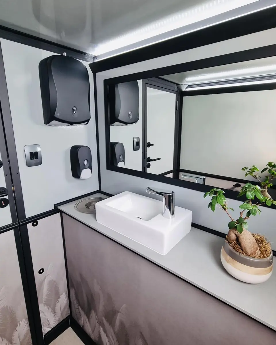 Restroom trailer vanity with a white vessel sink, mirror, soap and towel dispensers
