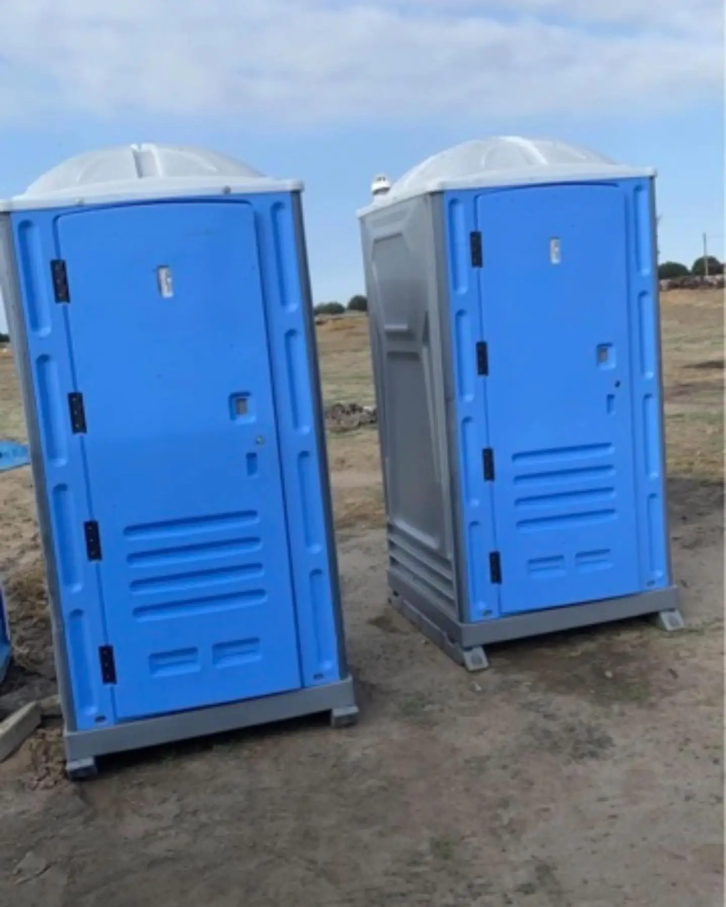 Two blue standard portable toilets with white roofs
