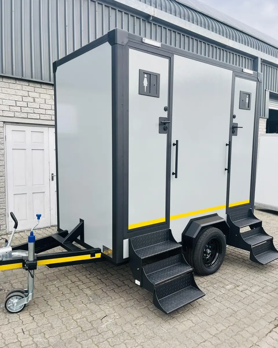Two-stall white and gray restroom trailer with fold-down steps